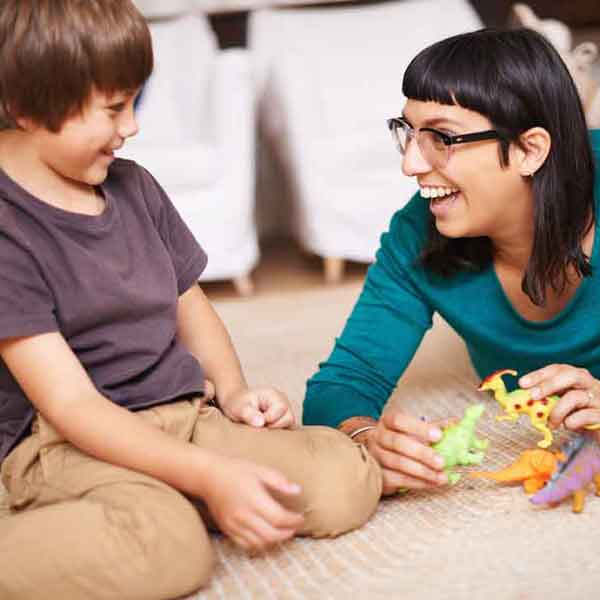 Therapist engaging a young child in play therapy using toys on the floor